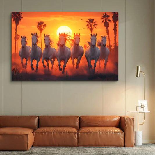 Canvas print of horses running at sunset with palm trees on a wall above a brown sofa.