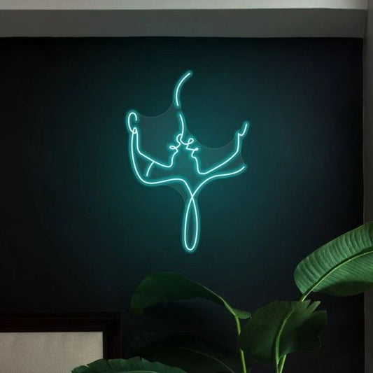 Couple Illustrator Neon Sign – Custom Neon Sign for Living Room Neon sign of a dancing figure on a dark wall with plants in the foreground
