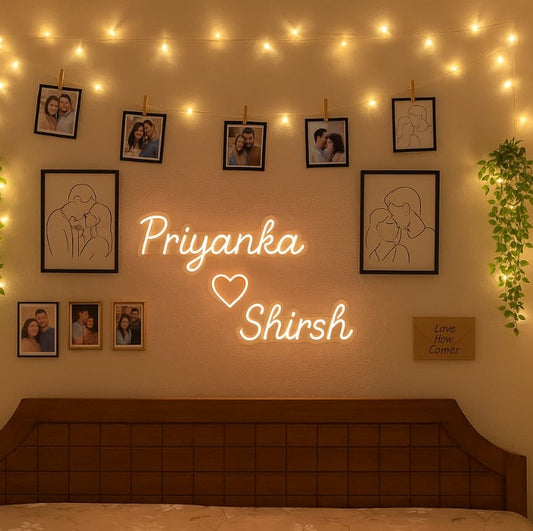 Couples Name Neon Light | Customized LED Neon Wall Decor Neon sign with 'Priyanka Shirsh' on a wall decorated with framed pictures and string lights.