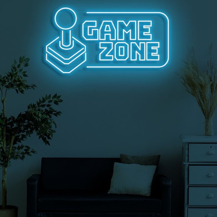 Handle Game Zone Neon Sign – Custom Neon Sign for Game Room 20 By 15 Inches Neon sign with 'Game Zone' on a wall in a dark room with a couch and plants.