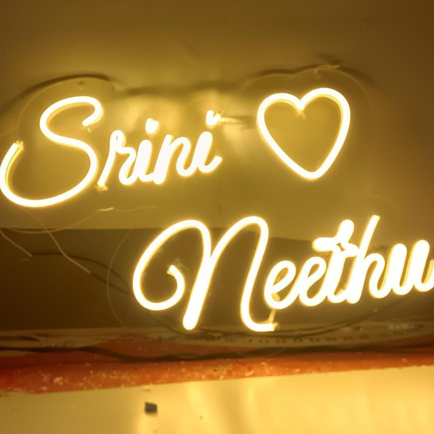 Neon sign with 'Sriniv' and 'Neethu' text on a white background