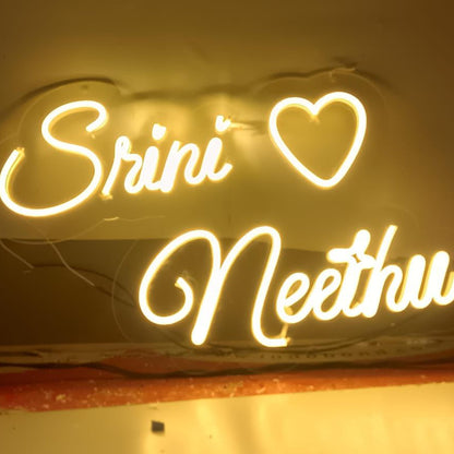 Neon sign with 'Sriniv' and 'Neethu' text on a white background