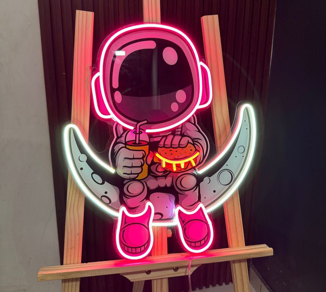 Neon sign of an astronaut holding a pizza on a wooden stand.
