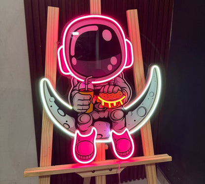Neon sign of an astronaut holding a pizza on a wooden stand.