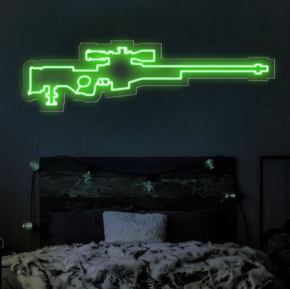 AWM Sniper Neon Sign  – Custom Neon Sign for Living Room 40 By 18 Inches Neon green gun-shaped light fixture on a dark wall above a bed.