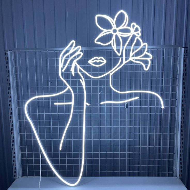 Beauty Girl Flower Neon Sign – Custom Neon Sign Gift for Girl Neon light art of a woman with flowers on her head against a blue tiled wall.