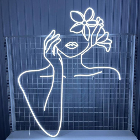 Beauty Girl Flower Neon Sign – Custom Neon Sign Gift for Girl Neon light art of a woman with flowers on her head against a blue tiled wall.