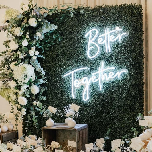 Better Together Neon Sign | Custom Neon Sign | Neon for Home Decor Neon sign with 'Better Together' text in a decorated room with flowers and greenery.