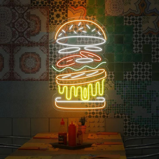 Burger Stuffing Neon Sign | Custom Neon Sign | Neon for Restaurants Sign Neon sign of a hamburger on a tiled wall with condiments on a table below.