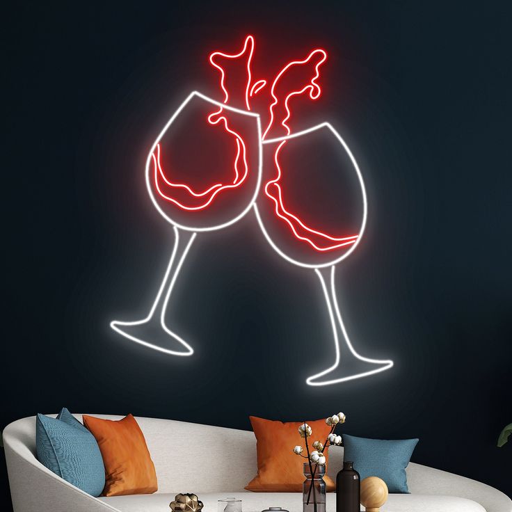 Cheers Red Wine Glass Neon Sign | Custom Neon Sign | Neon for Bar Neon sign of two clinking wine glasses on a dark wall above a sofa with colorful cushions.