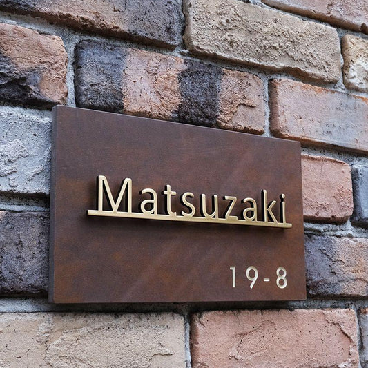 Premium rectangular metal address name plate with gold raised lettering, rustic brown finish and contemporary entrance design.