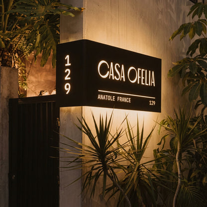 Modern L-shaped LED house number sign with personalised property name, street details, and warm white illumination mounted on a luxury villa entrance.