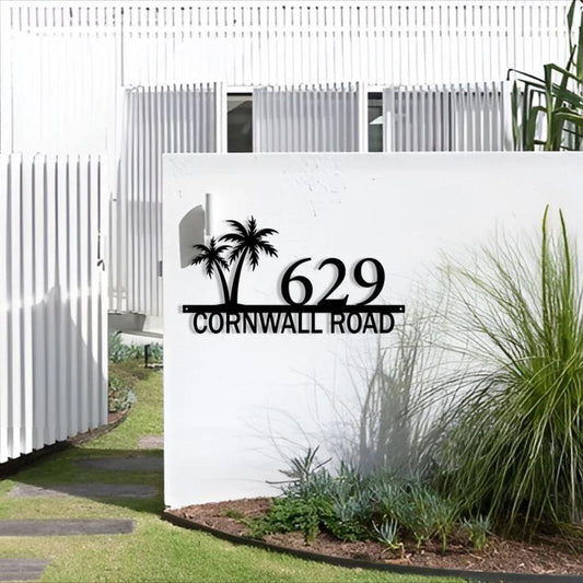Modern personalised metal address sign with raised black house numbers, street name and decorative palm trees for a contemporary home exterior.