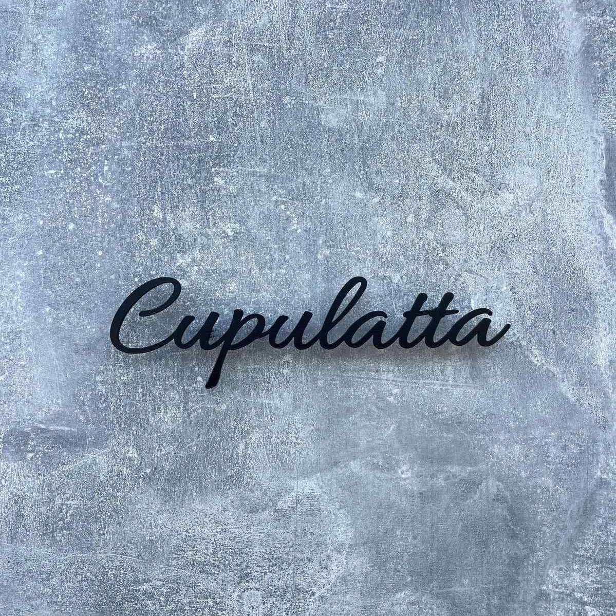 Modern 3D-style black cursive name signage mounted on a beige wall and wooden slat feature wall in a contemporary interior.