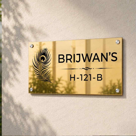 Golden personalised home name plate with family name and house number mounted on an exterior stone wall beside the main entrance.