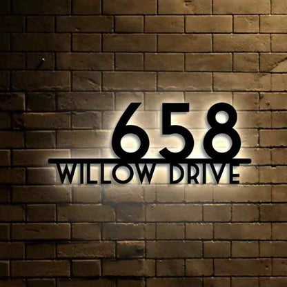 Modern LED house address plaque with raised black numbers and street name, mounted on a luxury home's exterior brick entrance.