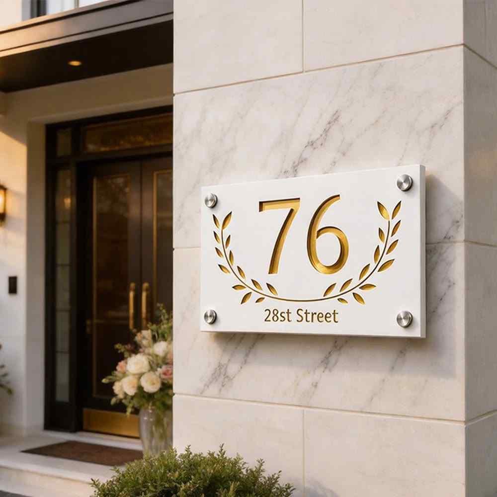 1. Modern personalised address plaque with gold numerals and decorative leaf detailing mounted on a luxury home entrance wall.