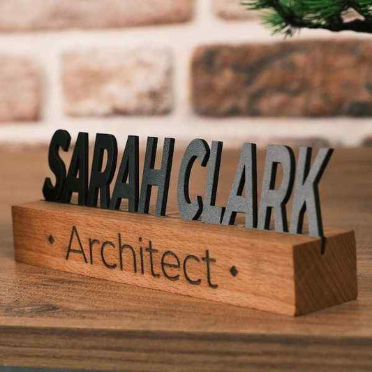Premium personalised wooden name sign for architects featuring raised black lettering on a natural wood base, displayed on an executive office desk.