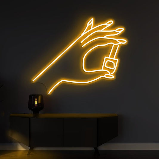 Finder Nail Art Neon Sign | Custom Neon Sign | Neon for Makeup Studio Neon light sculpture of a hand holding a light bulb on a dark wall.