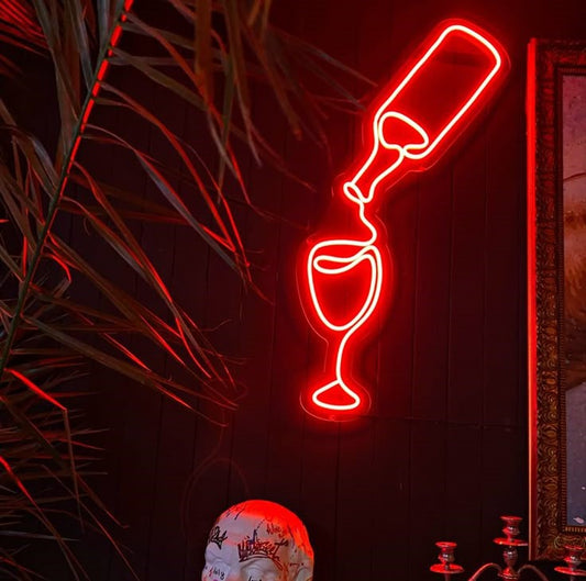 Glass and Bottle Neon Sign | Custom Neon Sign | Neon for Bar Decoration Neon light shaped like a wine bottle and glass pouring into each other on a dark background.