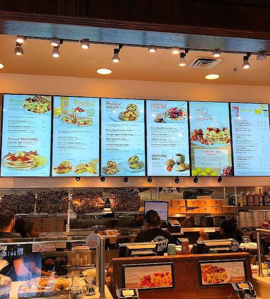 LED Digital Standee Video Display Signage for Branding, Advertising | Digital Advertising Display Screen | Led Video Standee 32" Wall Mounted Multicolored digital menu boards in a restaurant setting with food images and text.