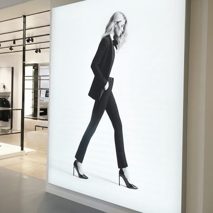 Large vertical backlit fabric light box showing fashion photography inside a retail boutique