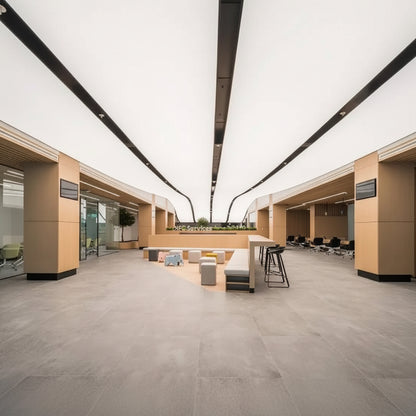 Large linear LED fabric ceiling panels providing soft white illumination in a contemporary commercial interior