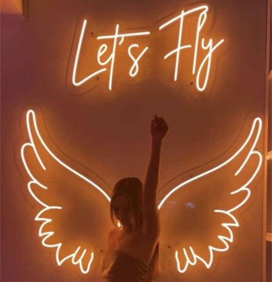 Lets Fly Wings Neon Sign | Custom Neon Sign | Neon for Living Room Decor Neon sign with 'Let's Fly' and wings against a warm background