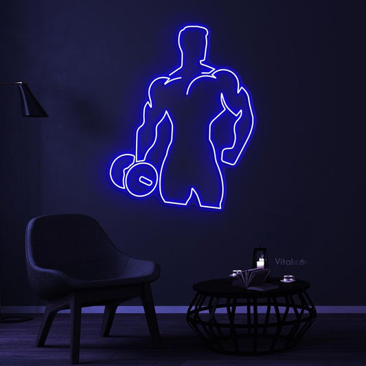 Men Hand Dumble Neon Sign | Custom Neon Sign | Neon for Gym Decoration Sign Neon sign of a muscular figure lifting weights in a dark room with a chair and small table.