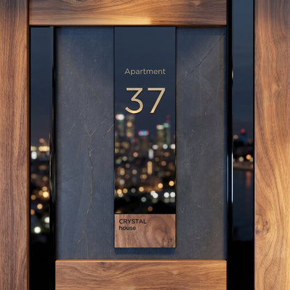 Contemporary apartment door number sign featuring gold 3D numerals on a black plaque with a natural wood accent, mounted on a luxury stone entrance wall.