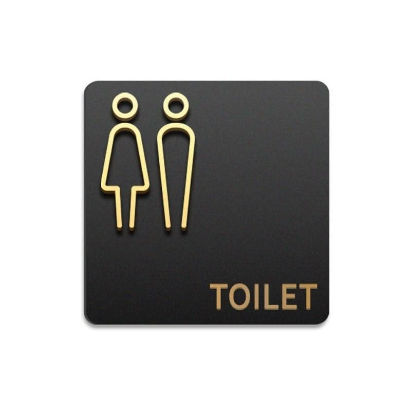 Premium black and gold restroom signage with raised male and female pictograms displayed on wooden, dark marble and textured stone walls.