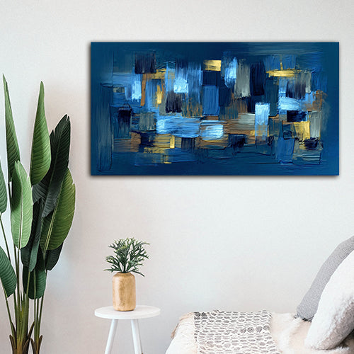 Modern blue abstract geometric canvas wall painting with textured brush strokes for living room and office wall decor Abstract blue painting on a white wall with a plant and small table in the foreground.