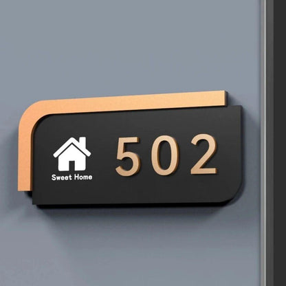 1. Premium black and gold house number sign with rounded corners, metallic gold edging and raised address numbers, displayed on dark stone and wooden entrance walls.