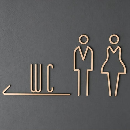 Premium gold toilet signage featuring WC lettering and outlined male and female figures on dark stone, grey textured and wooden wall backgrounds.