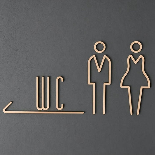 Premium gold toilet signage featuring WC lettering and outlined male and female figures on dark stone, grey textured and wooden wall backgrounds.
