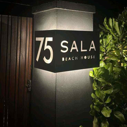 Premium black LED address plaque with glowing house number 75 and personalised beach house lettering beside a contemporary entrance.