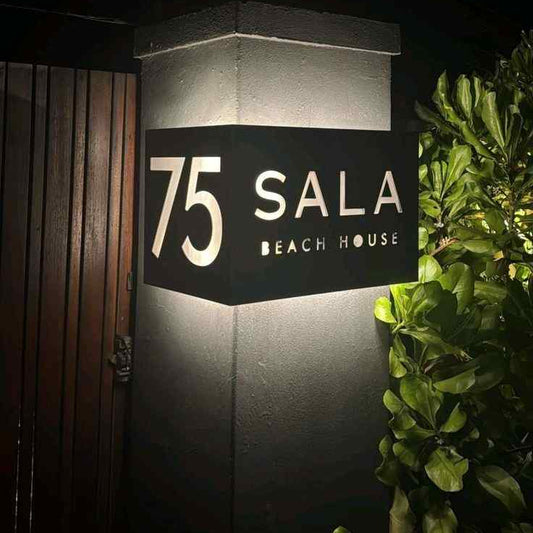 Premium black LED address plaque with glowing house number 75 and personalised beach house lettering beside a contemporary entrance.