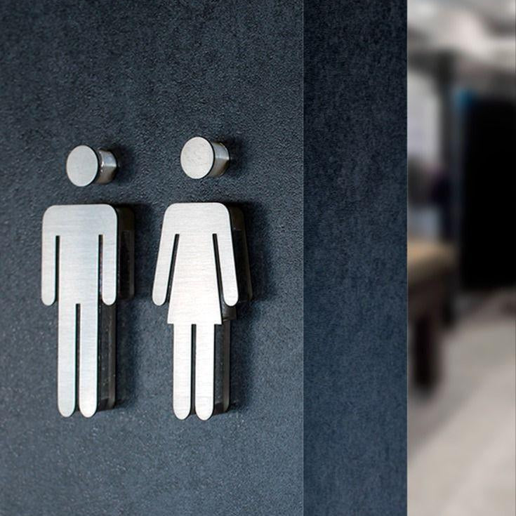 Premium silver toilet signage for men and women displayed on wooden, beige stone and dark marble walls in modern commercial interiors