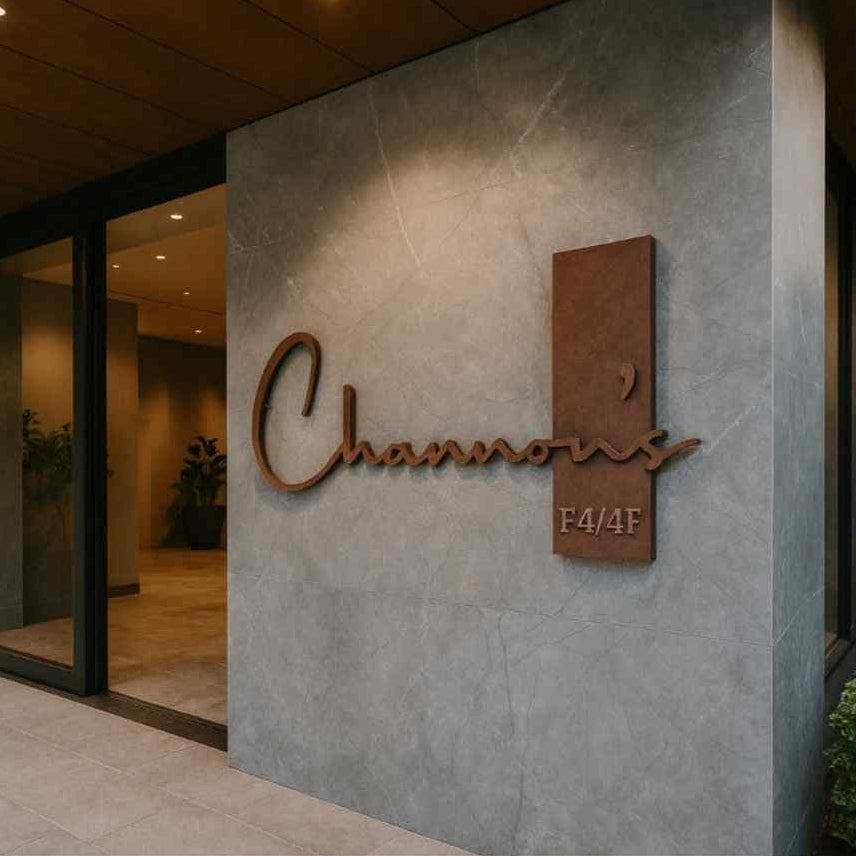 Custom designer house name sign with warm backlighting, raised script lettering and a matching vertical floor number plaque on a contemporary exterior wall.
