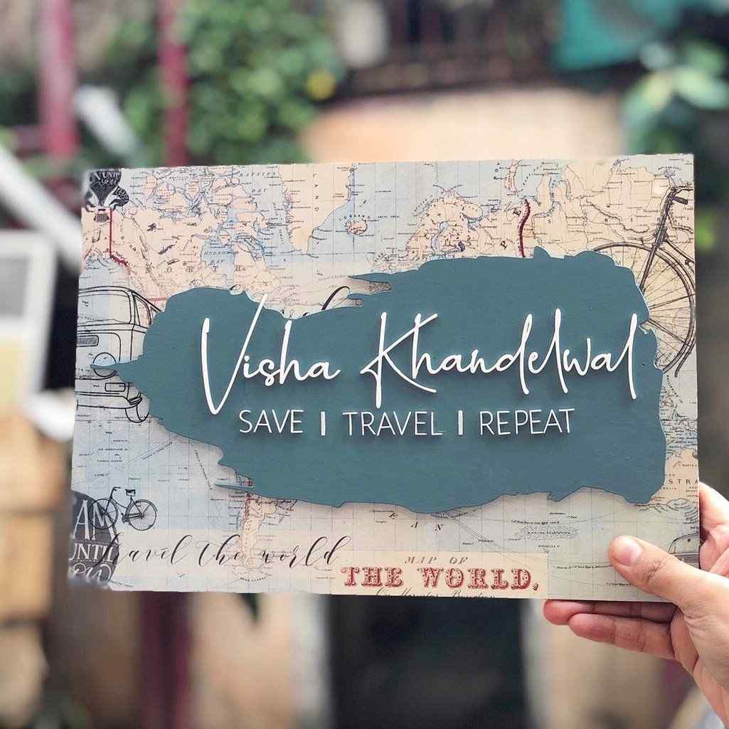 Custom travel-themed wall nameplate with vintage map artwork, blue central panel, personalized white script lettering and travel-inspired typography.