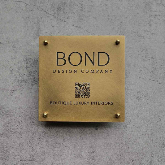 Custom gold office signage with company logo, QR code and business name displayed on a wooden feature wall and dark marble entrance.