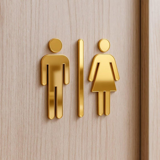 Modern gold toilet signs for men and women displayed against marble, dark stone and wooden wall finishes in contemporary commercial interiors.