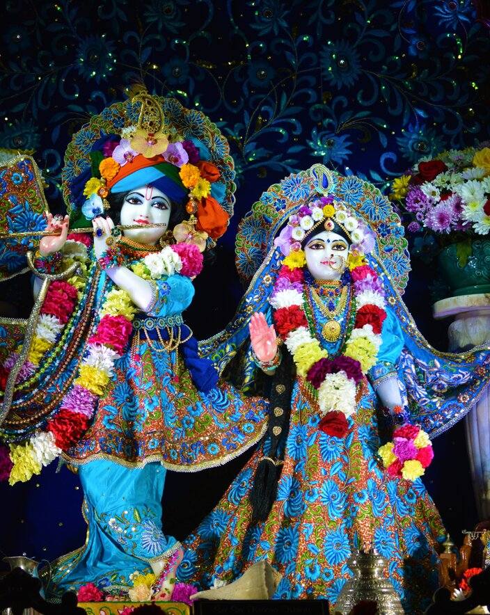 Radha Krishna Wallpaper | Instant Peel Stick Spiritual Art Colorful statues of deities adorned with flowers against a dark background