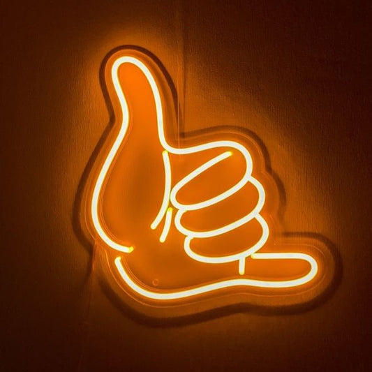 Shaka Hand Neon Sign | Custom Neon Sign | Neon for Living Room Decor Neon sign shaped like a hand giving a thumbs up on a brown background