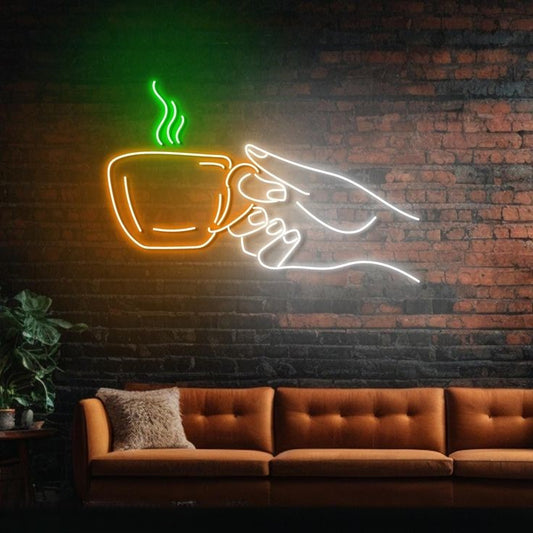 Tea Hand Neon Sign | Custom Neon Sign | Neon for Restaurant, Cafe Neon sign of a hand holding a coffee cup against a brick wall with a brown sofa.