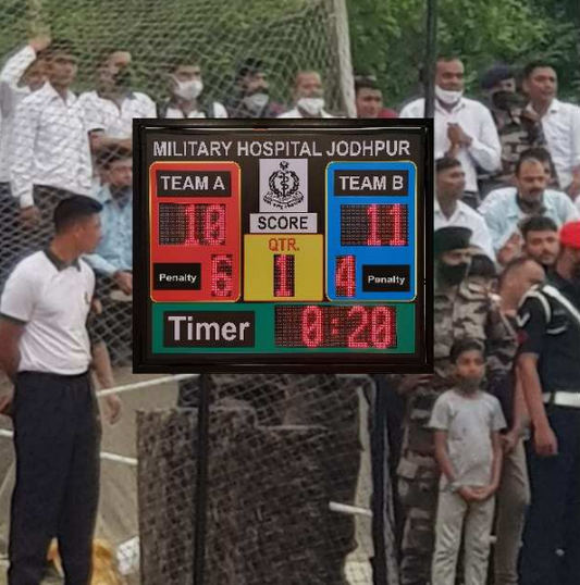 The Seven Colours LED Sports Scoreboard | LED Running Sports Scoreboard for Cricket | Led Cricket Scoreboard for Football, Volleyball, Hockey, Basketball, Badminton, Tennis Digital scoreboard displaying a sports match between 'Team A' and 'Team B' with spectators in the background.