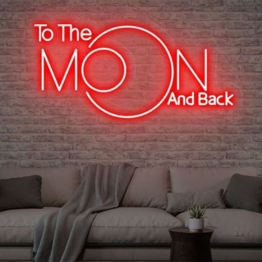 To the Moon and Black Neon Sign | Custom Neon Sign | Neon for Bar, Restaurant Neon sign with 'To The Moon And Back' on a brick wall above a sofa.