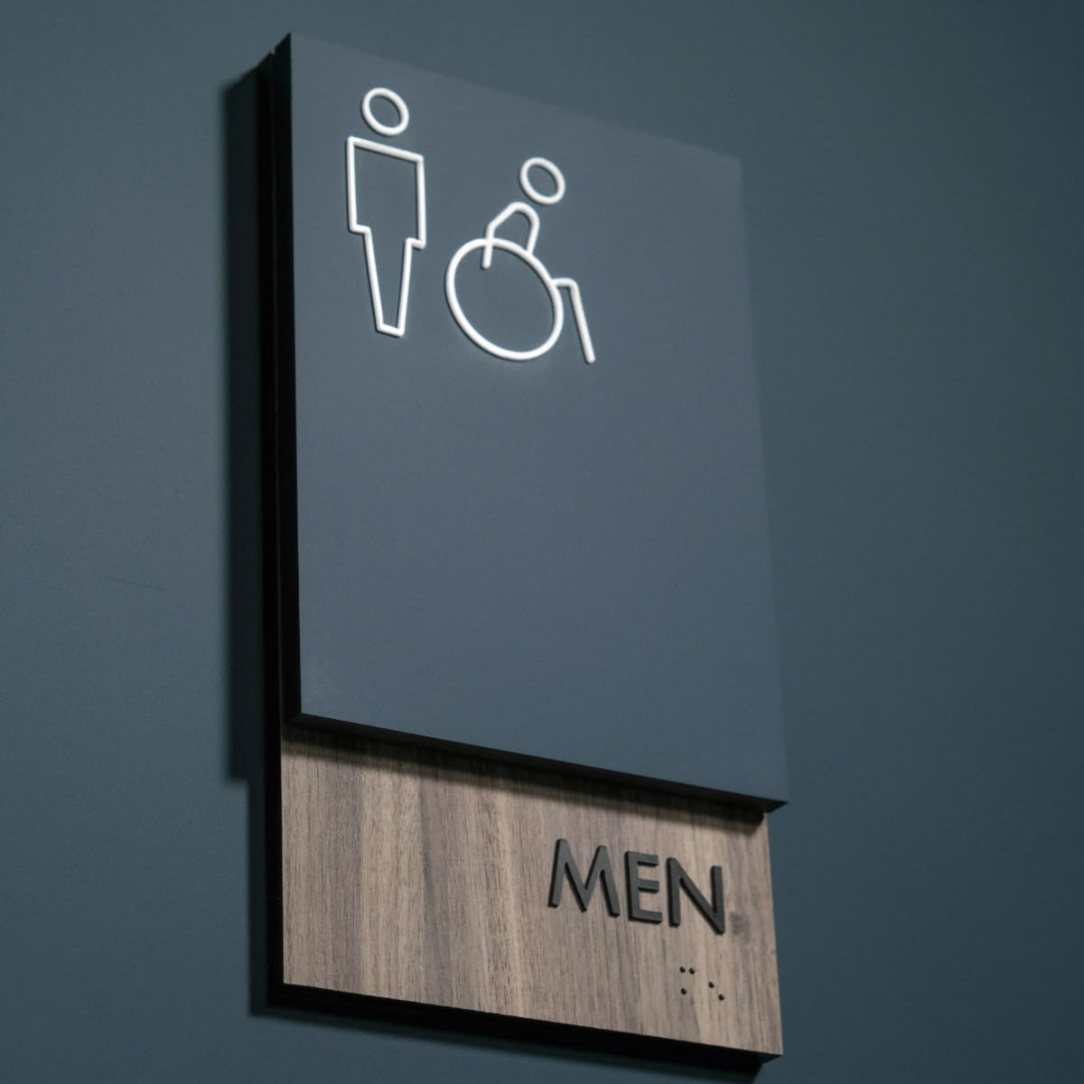 Accessible men restroom sign with wheelchair symbol and braille signage
