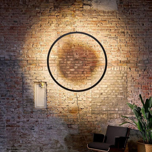 Industrial circular LED ring light with halo wall illumination for modern interiors.