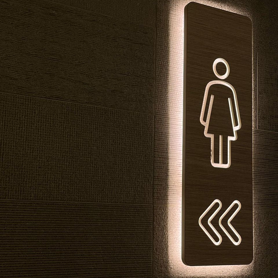 LED backlit wooden restroom sign with female icon and directional arrows
